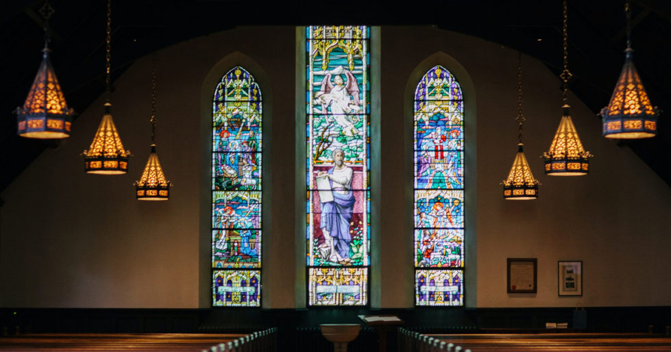 3 stained glass windows at the back of a church