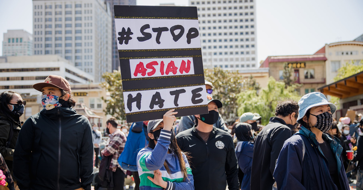 A woman holds up a sign which says #Stop Asian Hate