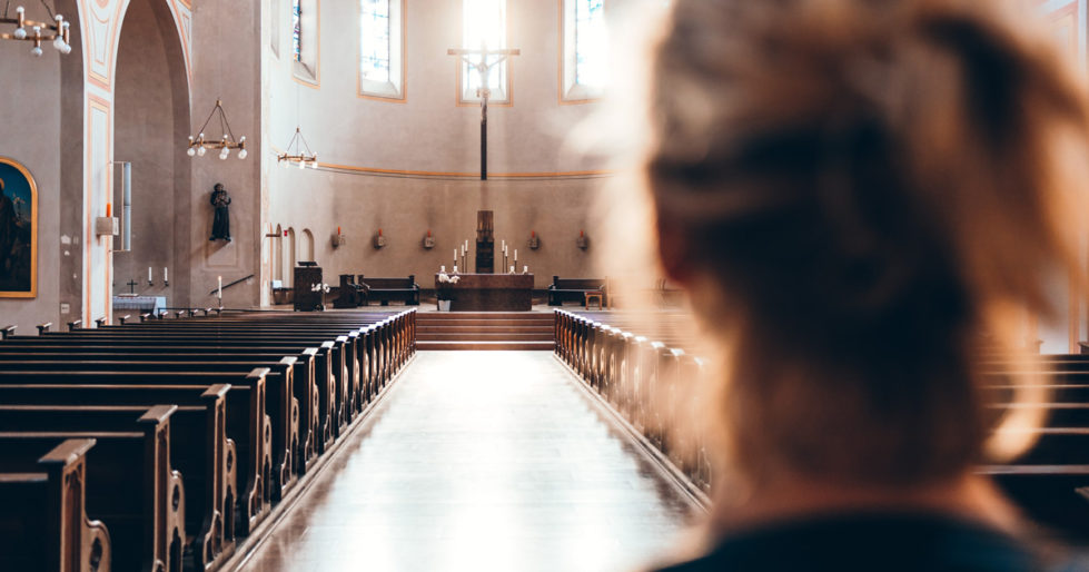 a closeup of a woman's head as she looks down an aisle of a Catholic church