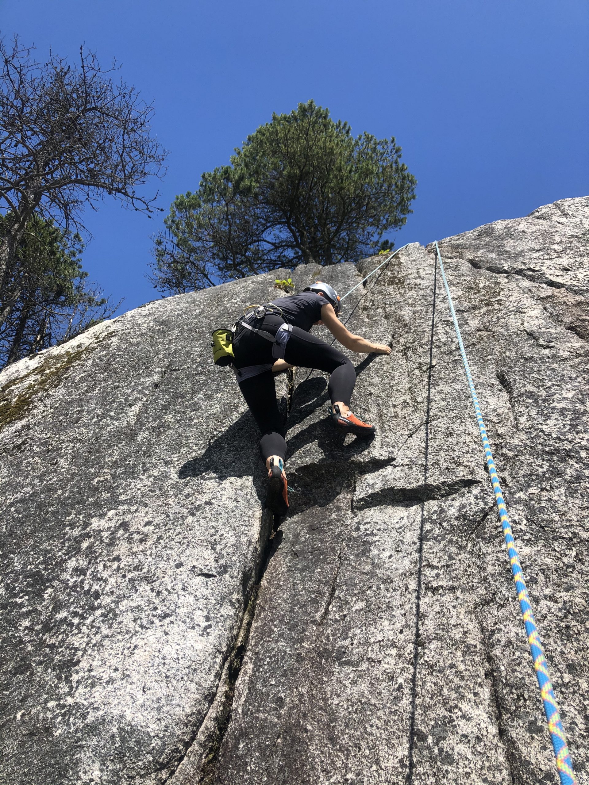 A person rock-climbing up a steep, sheer rockface