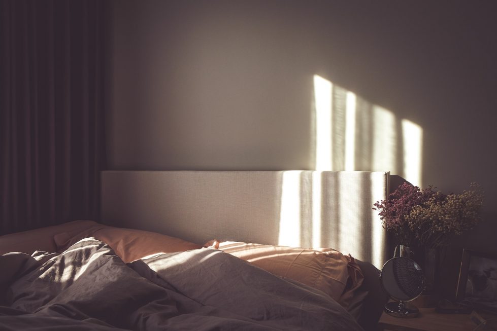 bed in front of wall with sunlight