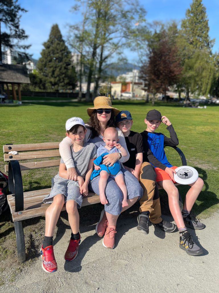 Bryana sits on a bench with her four boys
