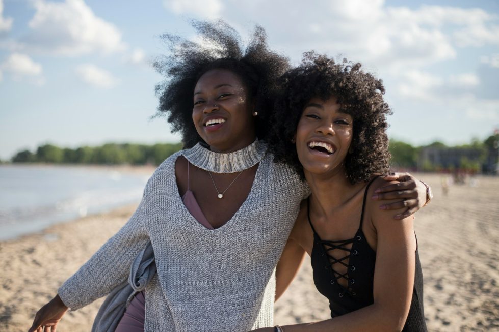 2 black women laughing with arms around each other